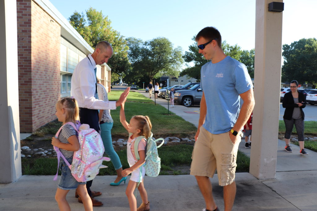 Jason Chicoine Clarmar Principal high fives students, parent smiling