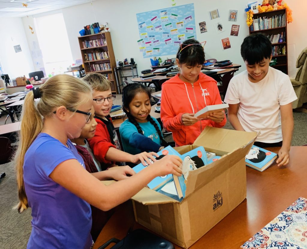 students pulling new books out of a box